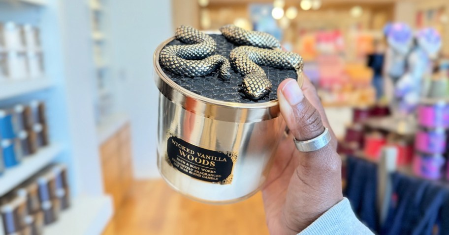 woman holding a bath and body works halloween candle with a snake decal on the lid