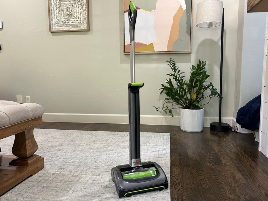 gray and green bissel vacuum standing in living room 