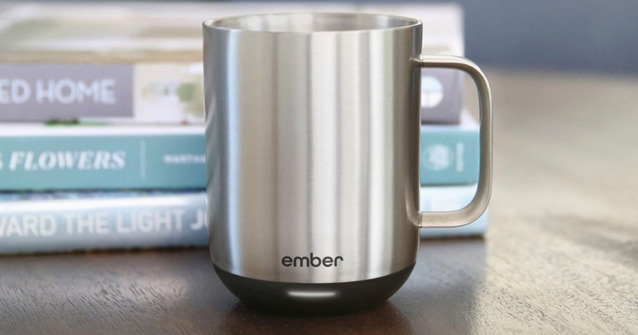 stainless steel mug sitting on table with books