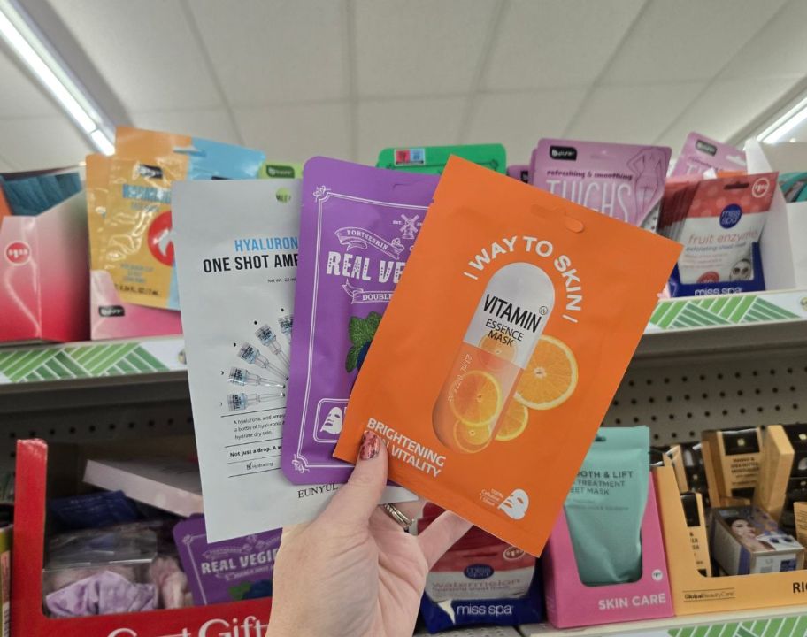 a womans hand holding 3 face mask packets