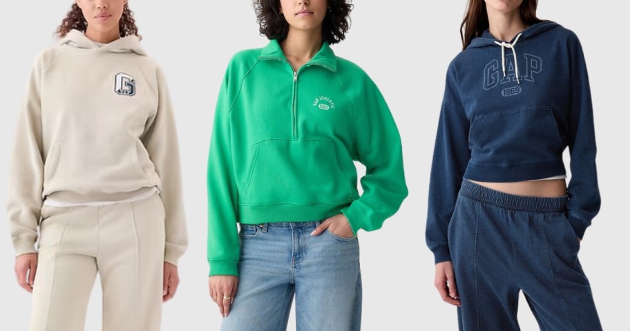 woman wearing a beige GAP hoodie, woman wearing a green quarter zip pullover sweatshirt, and woman wearing a cropped blue GAP logo hoodie