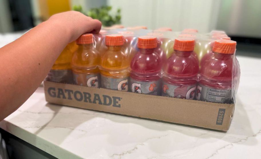 a kid grabbing a gatorade bottle from a shrink wrapped 24 count pack