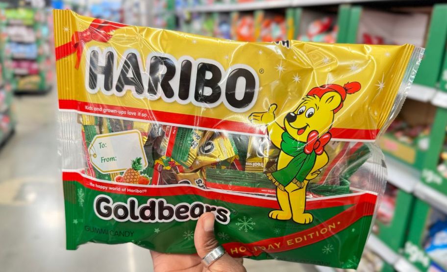 a womans hand holding a holiday mix bag of haribo goldbears snack packs