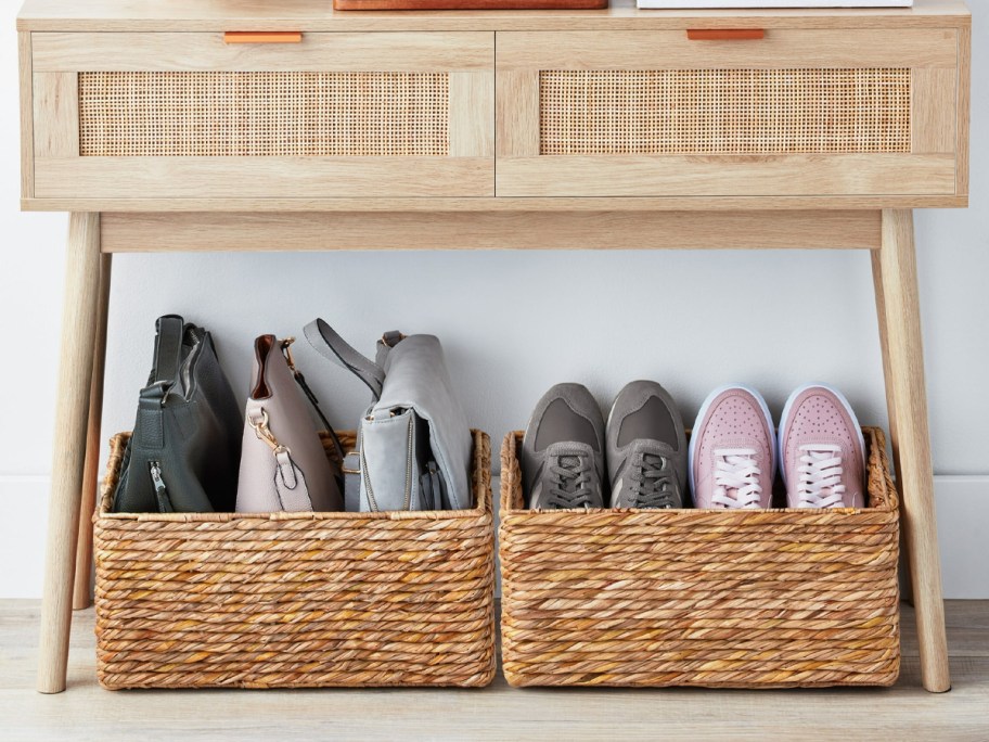 two woven baskets full of shoes and purses under table