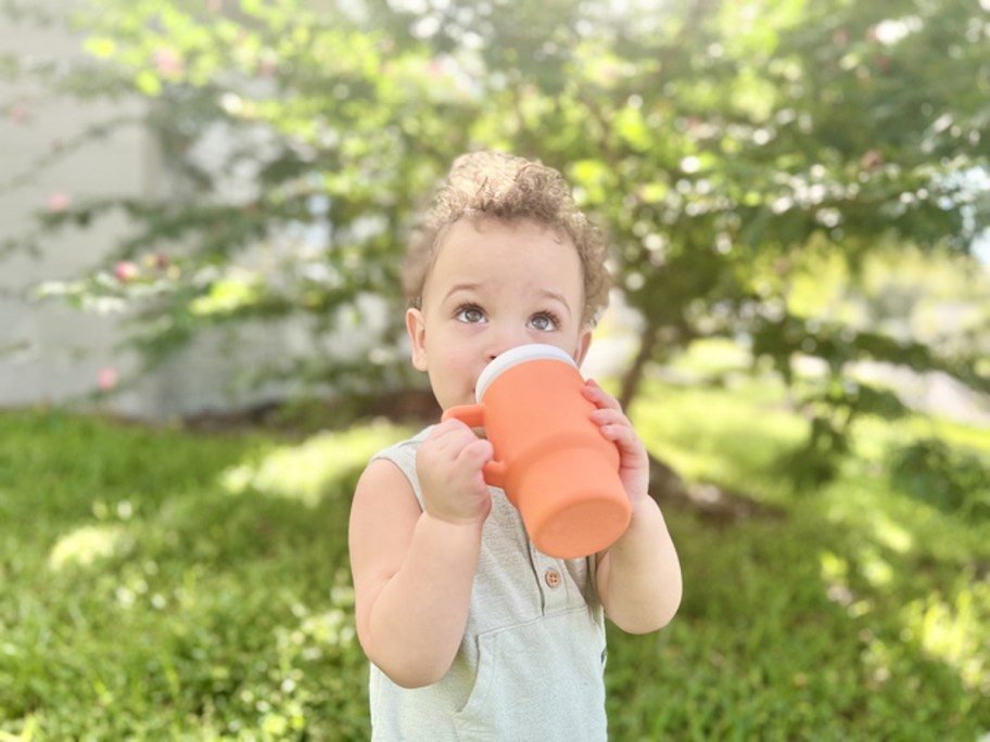 toddler boy sipping from orange tumbler