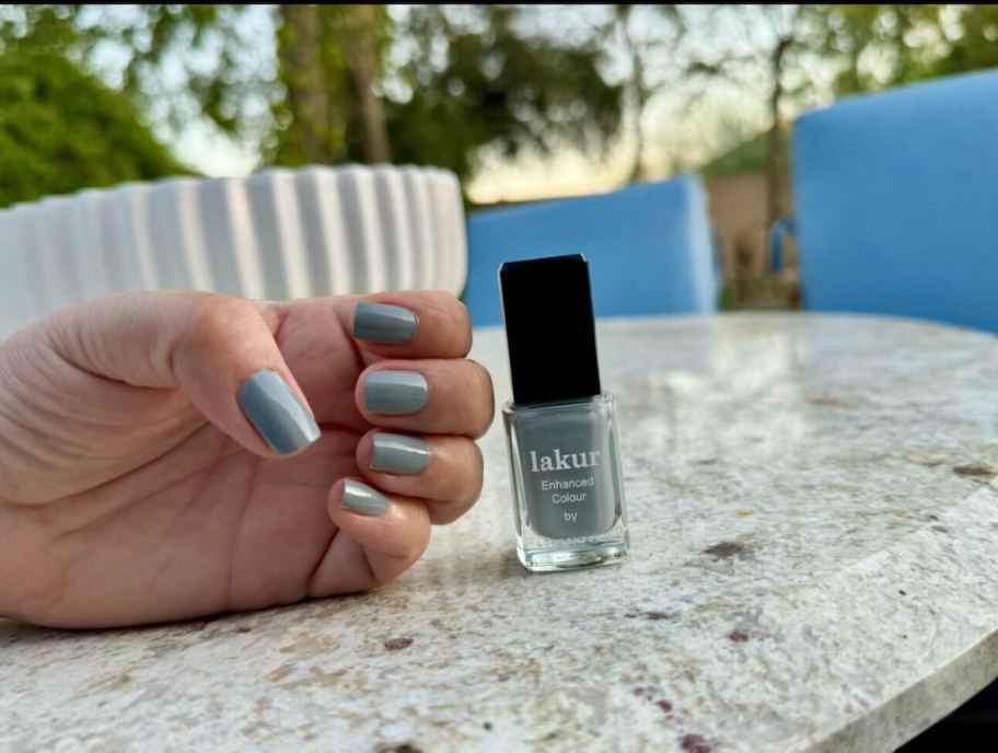 hand showing nails with bottle of polish sitting on table 