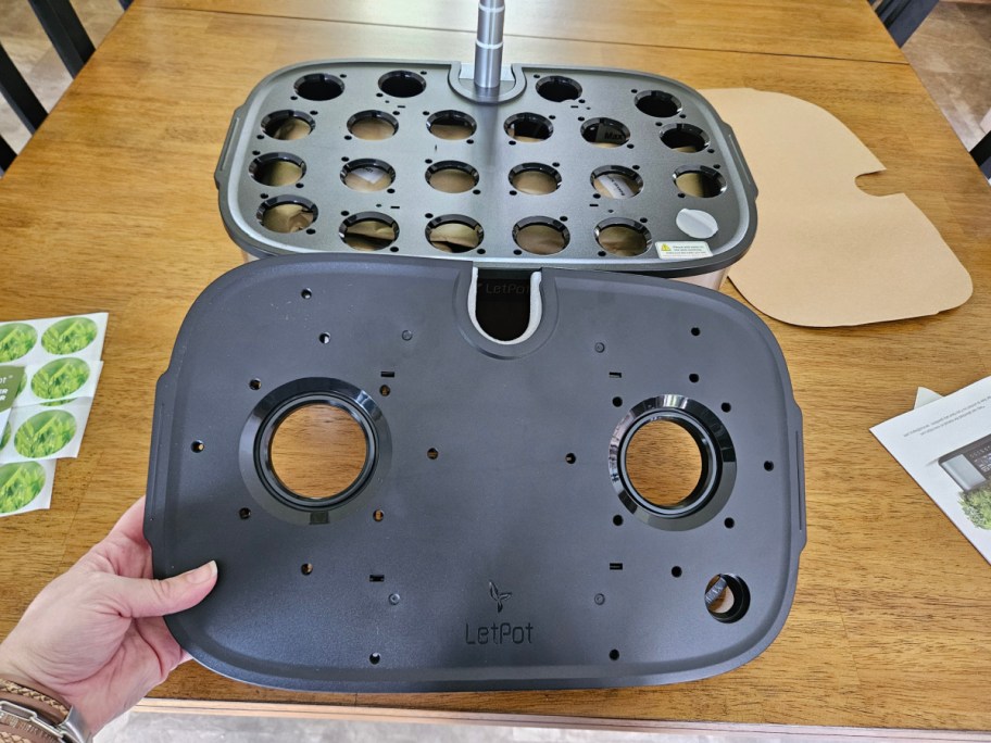 hand holding a tray in front of a letpot hydroponics growing system sitting on a table