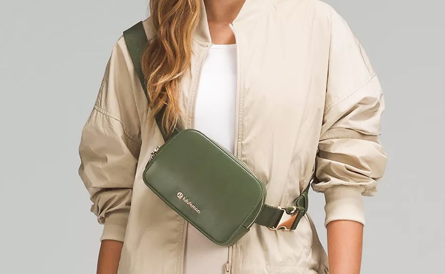 woman in a tan jacket with an olive green lululemon belt bag