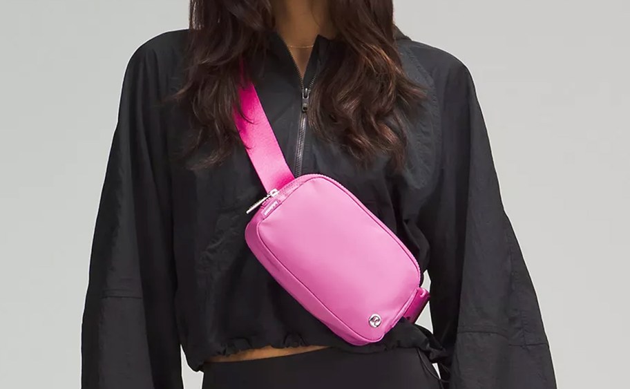 woman in a black jacket with a pink belt bag