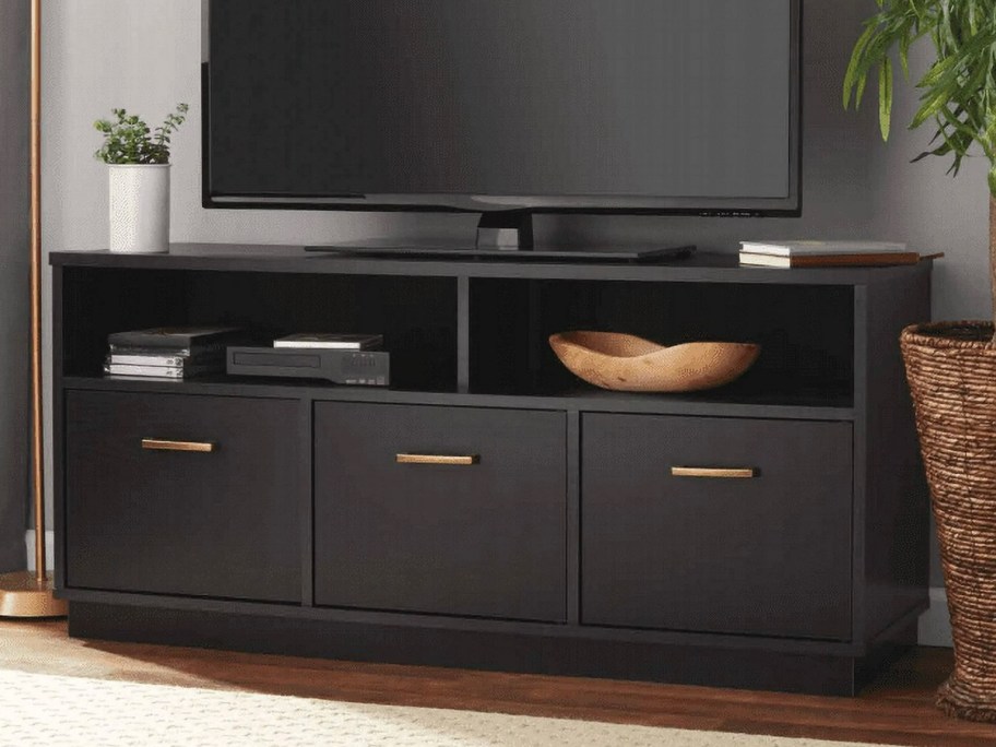 black tv console with large tv on top 