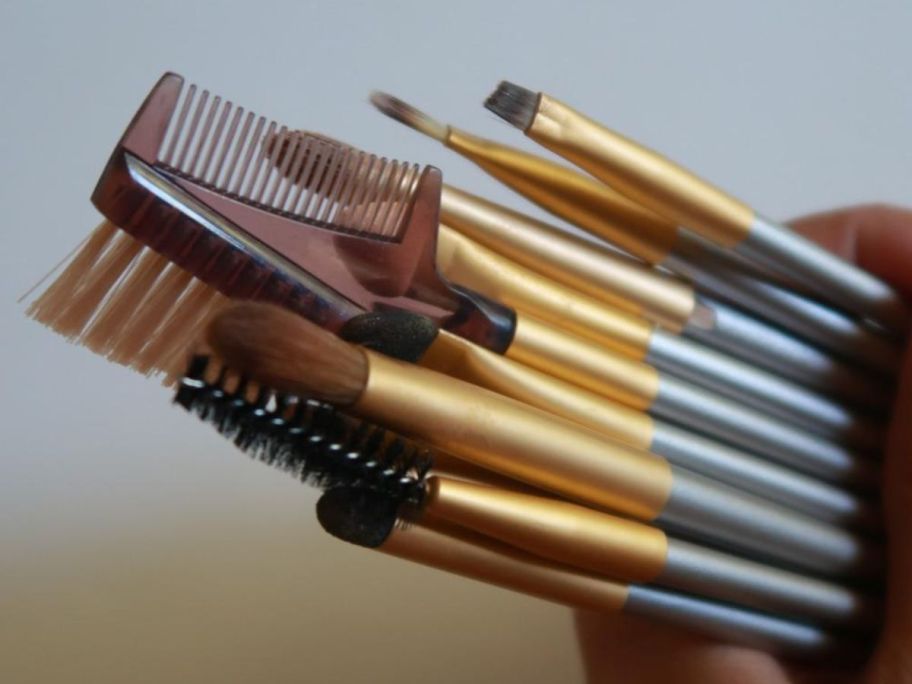 a hand golding a set of matching makeup brushes