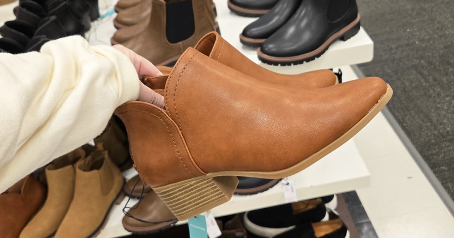 hand holding up a tan pair of booties in store