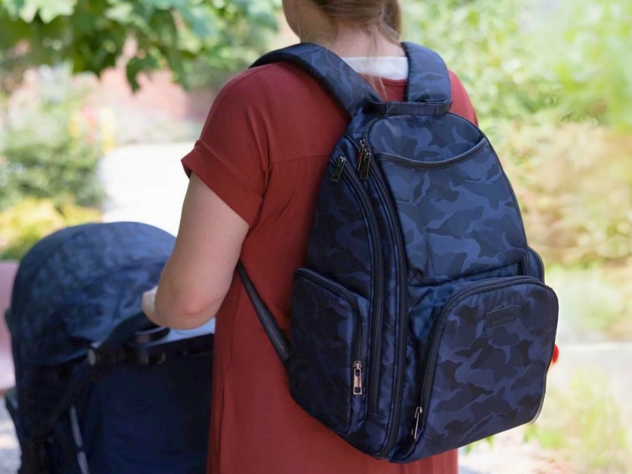 woman wearing a blue camo diaper bag backpack pushing a blue baby stroller