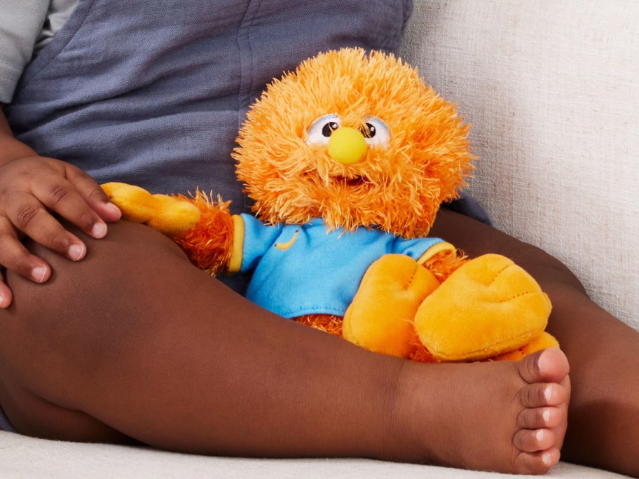 toddler sitting with orange plush Herbie doll