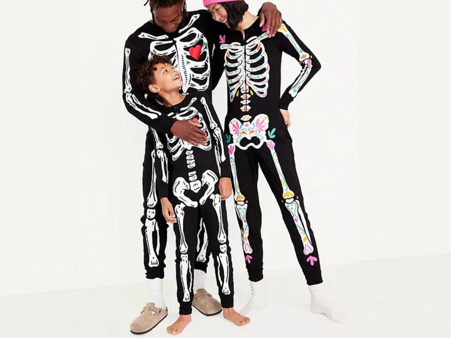 man, woman, and child wearing matching snug fit skeleton pajamas 