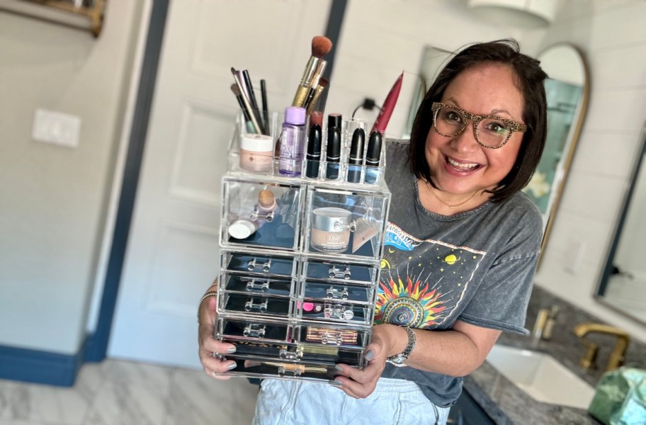 smiling woman wearing glasses and holding a sorbus makeup organizer filled with makeup