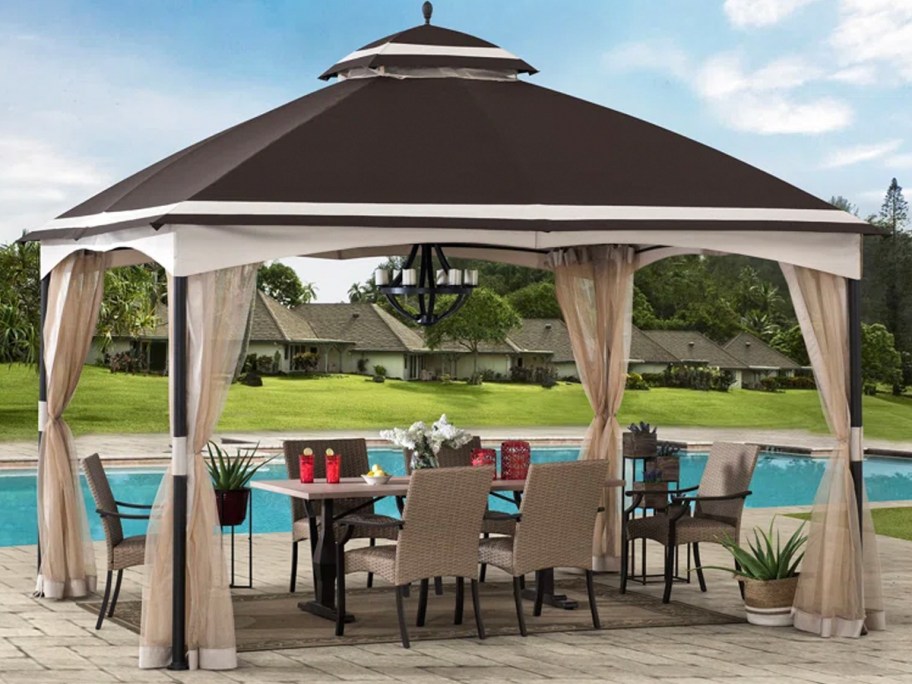 tan and beige gazebo next to pool with patio set underneath