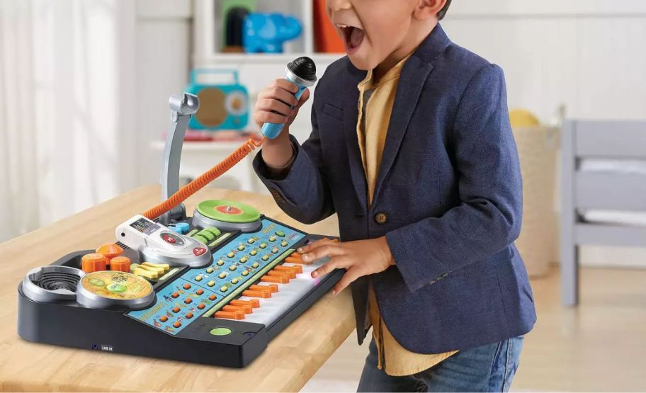 a little boy singing onto the mic and playing keyboard