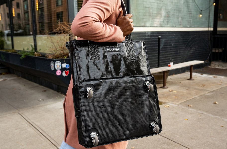 woman wearing Hulken tote bag on her shoulder as she walks