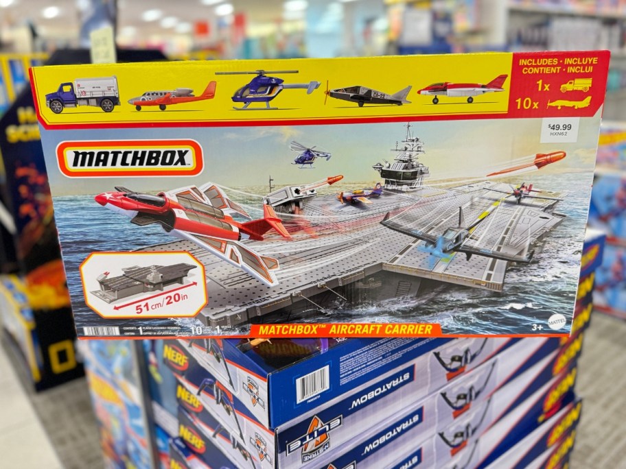 a box with a Mattel Matchbox Aircraft Carrier Model & Play Set stacked on top of more in a store