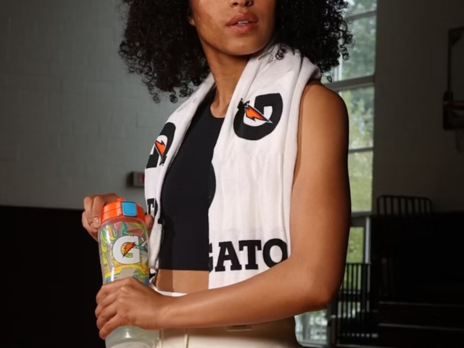 woman with a white and black Gatorade logo towel around her neck and shoulders holding a Gatorade water bottle