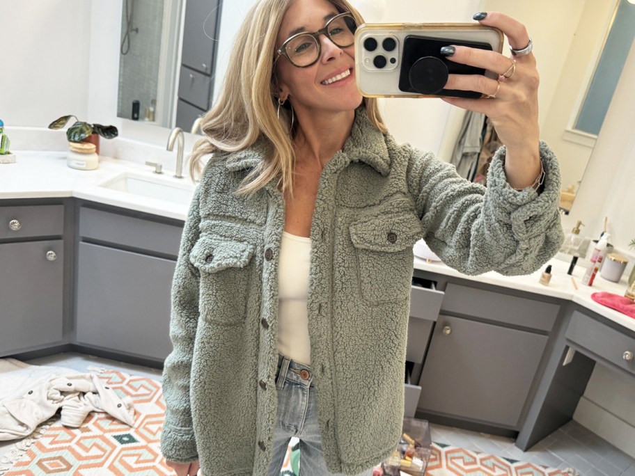 woman taking photo in mirror wearing green sherpa jacket