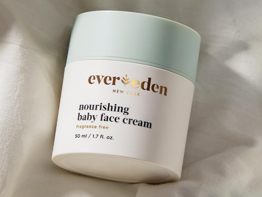 white and blue jar of Evereden Nourishing Baby Face Moisturizer on a cream blanket