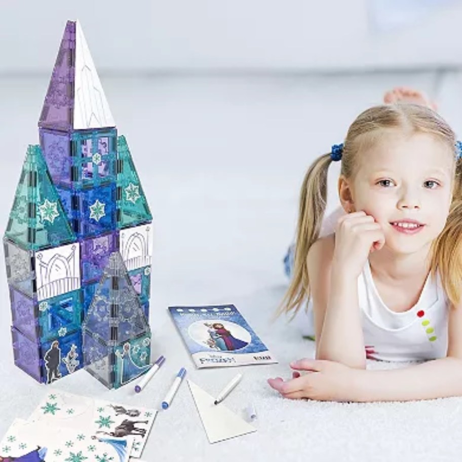 little girl sitting by a castle made from magnetic tiles