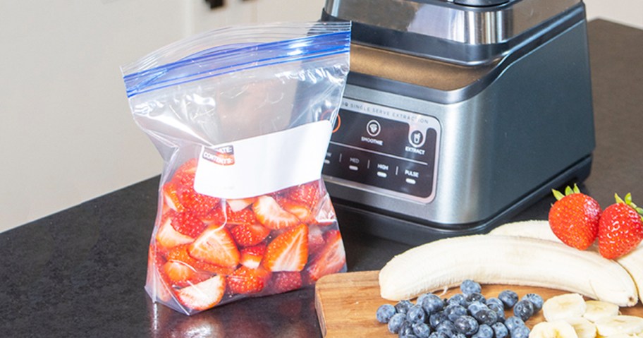 quart sized bag filled with strawberries on counter near blender