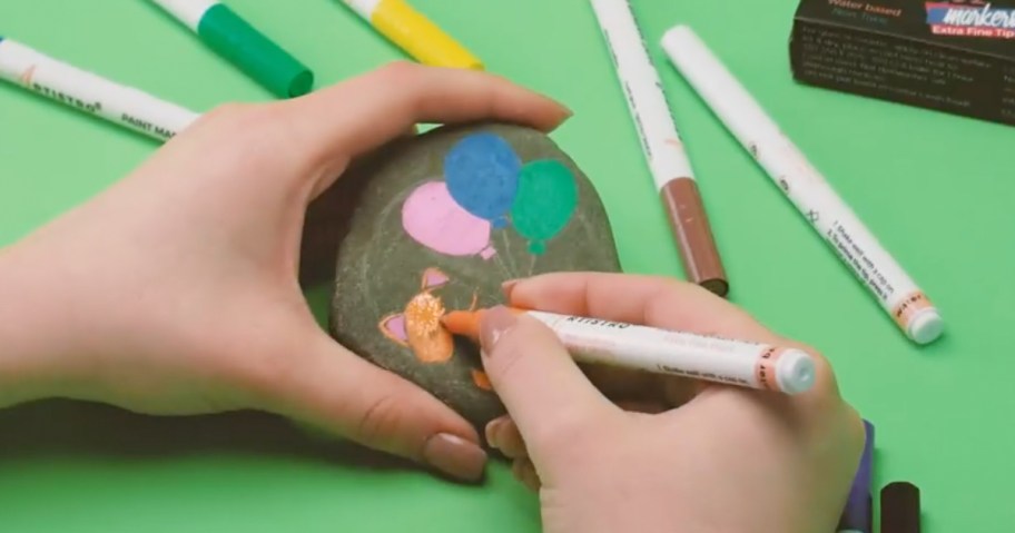 hands holding rock with paint pens