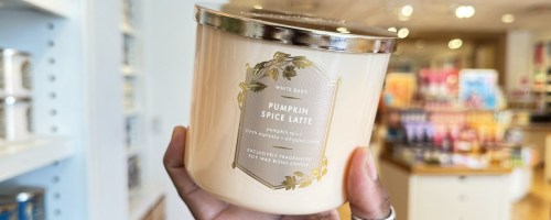 hand holding up a pumpkin spice latte 3-wick candle in store