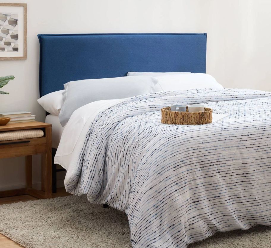 a bed with a blue fabric covered headboard shown in a bedroom