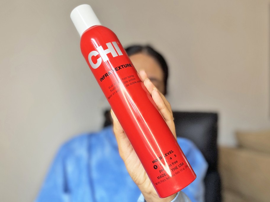 woman holding up a red can of CHI Hair Spray