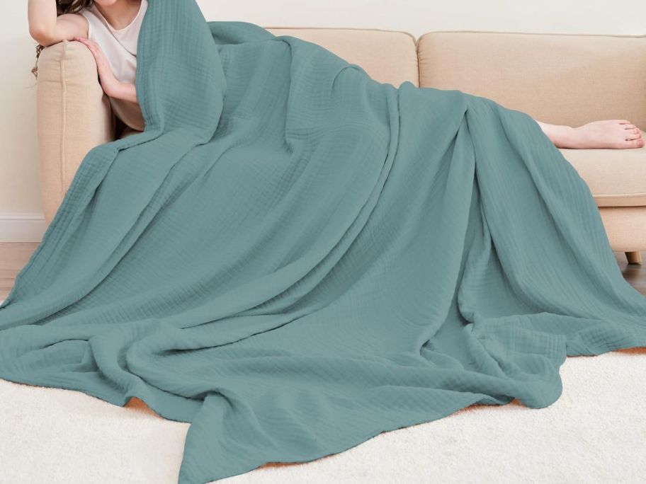 woman laying with Cosy Family 4-Layer Muslin Bed Blanket on couch