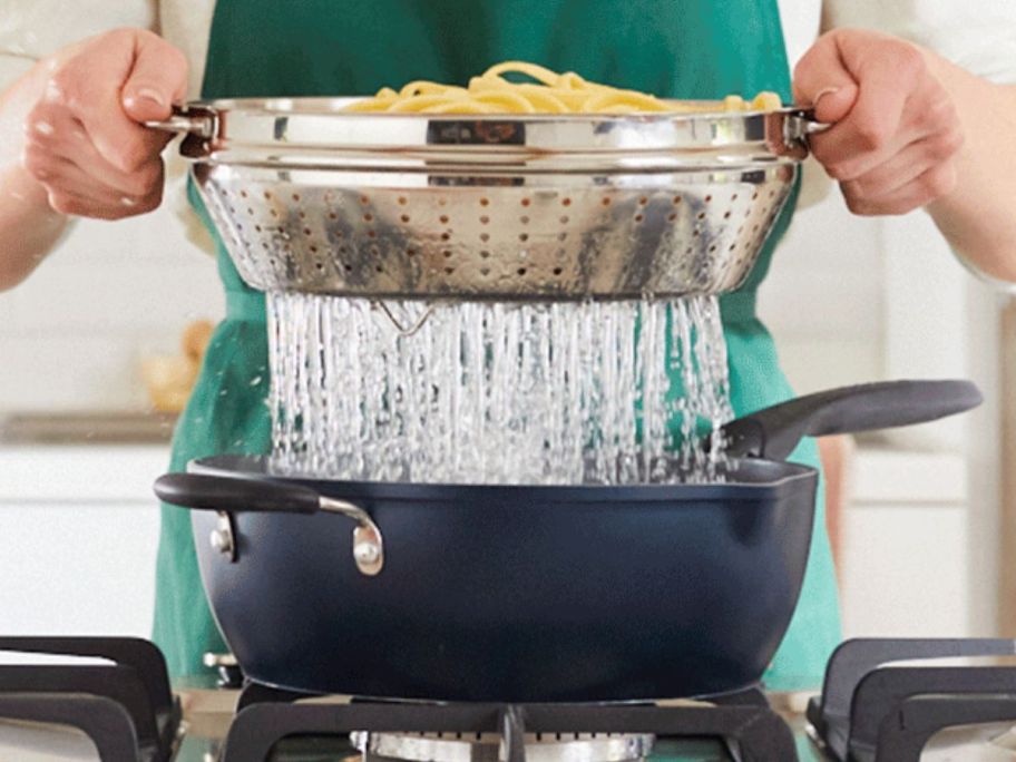 Woman lifting the metal steaming tray with pasta in it out of a Preferred Pan filled with boiling water.