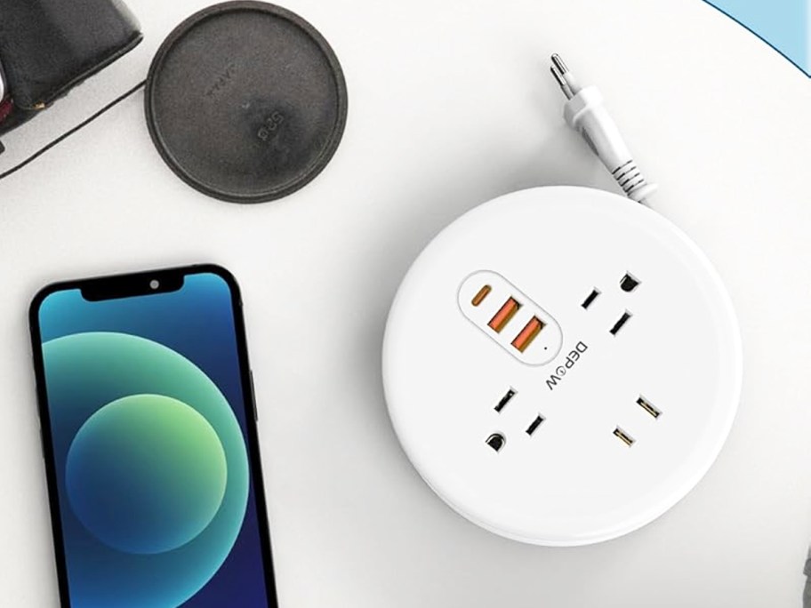 round white power strip charging station on white table near iphone