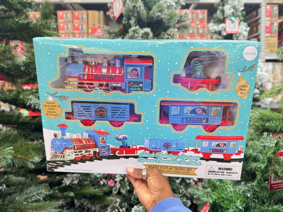 A person holding up a box containing a Stitch Express Train Set