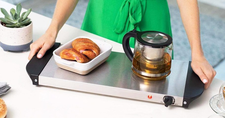 woman placing baked goods and teapot on warming tray