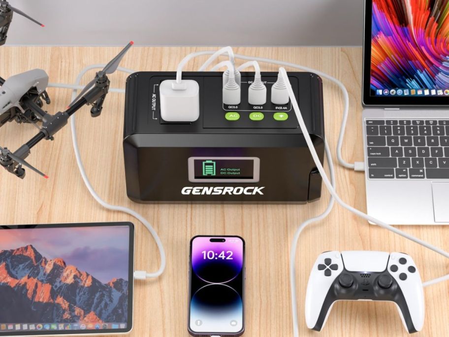 A Gensrock portable power station on a desk with many devices plugged into it