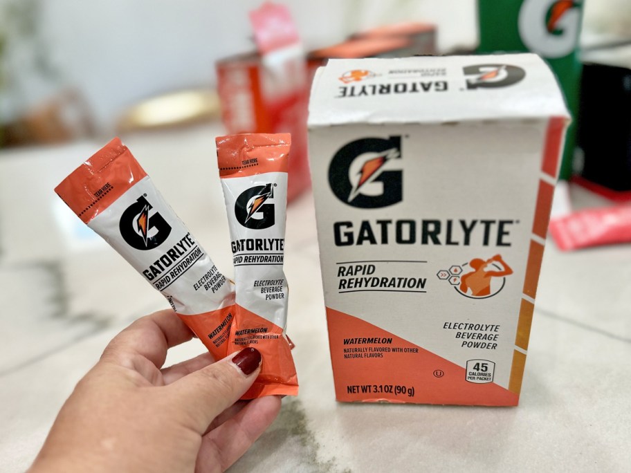 hand holding up two Gatorade Gatorlyte Sticks near their box