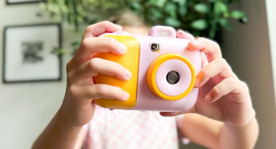 Girl using instant camera in pink