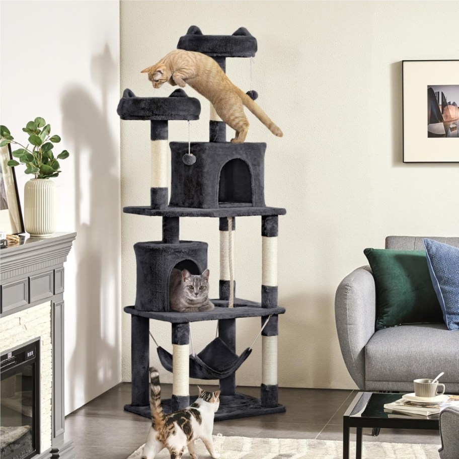 a tall dark grey and white cat tree in a living room with cats on it