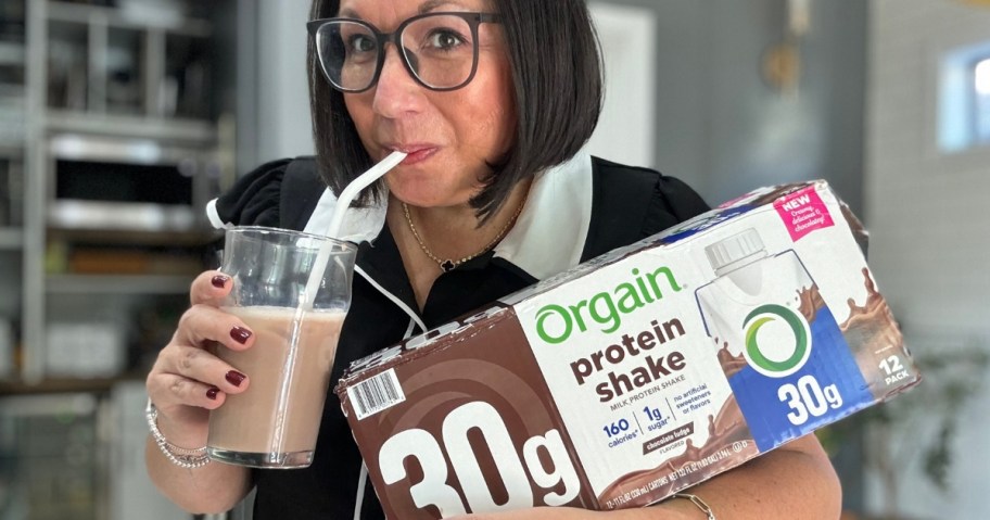 Woman holding a box of Organ Shakes while drinking from a glass with a straw