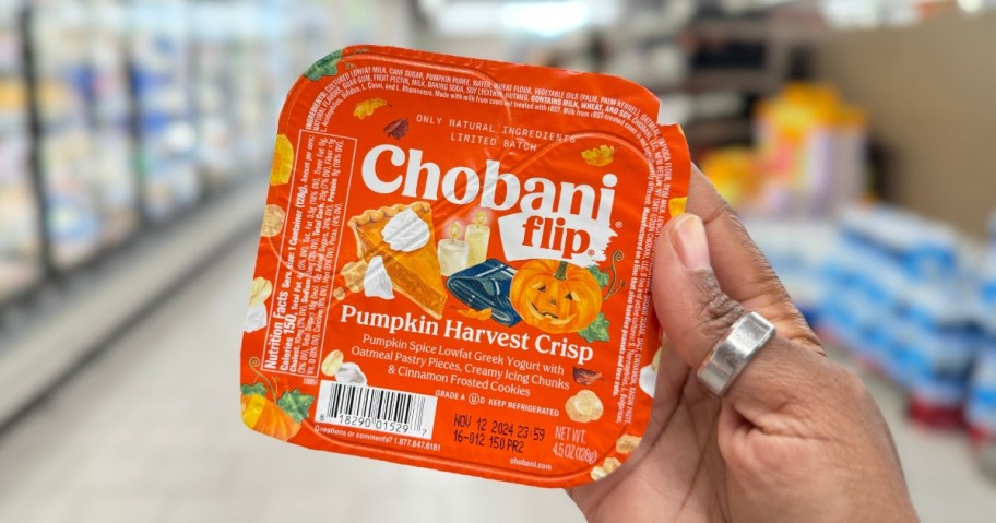 hand holding an orange and white container of Chobani Flip Pumpkin Harvest Crisp flavor