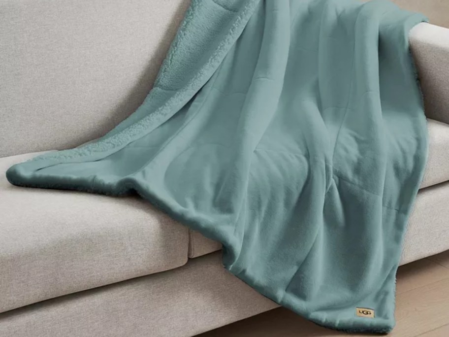 a green UGG blanket on a tan sofa