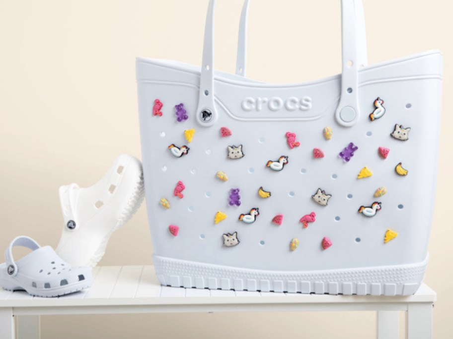 white crocs next to a light blue crocs tote full of colorful charms