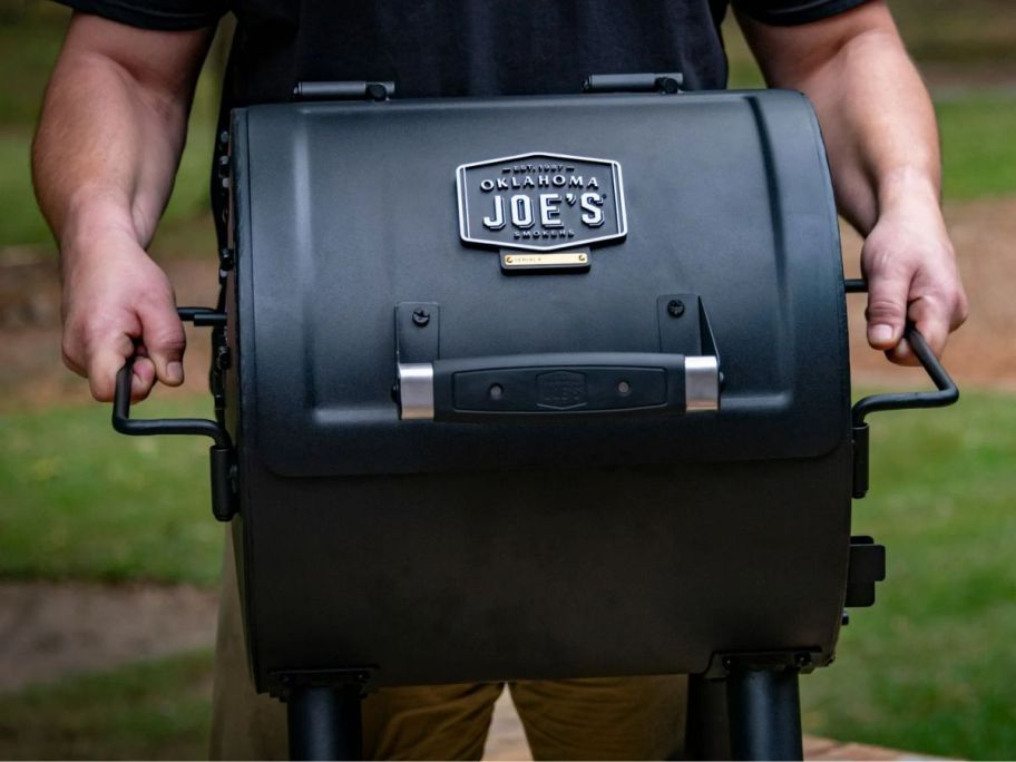 a man carrying a hitch portable charcoal grill