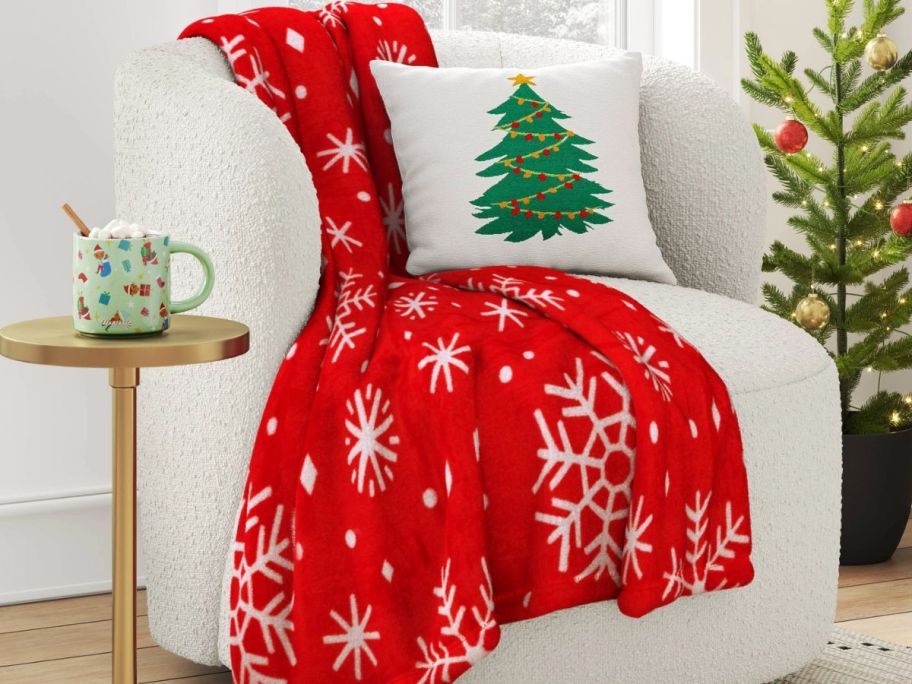 a snowflake print blanket draped over a sofa and shown with throw pillows