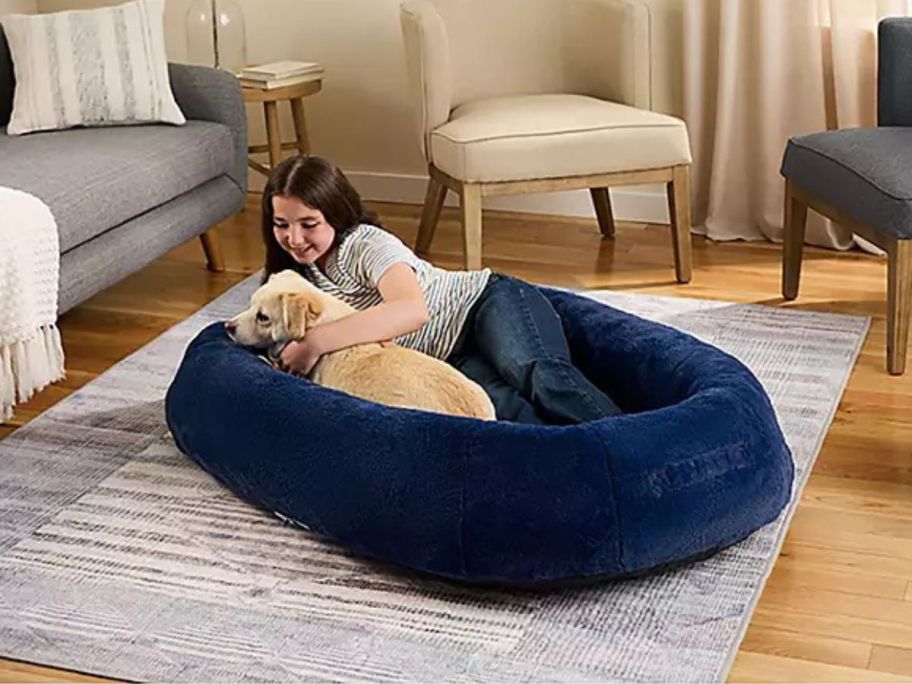 Child in a kid-size pet bed with a dog