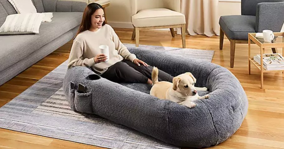 woman and dog sitting in dog bed